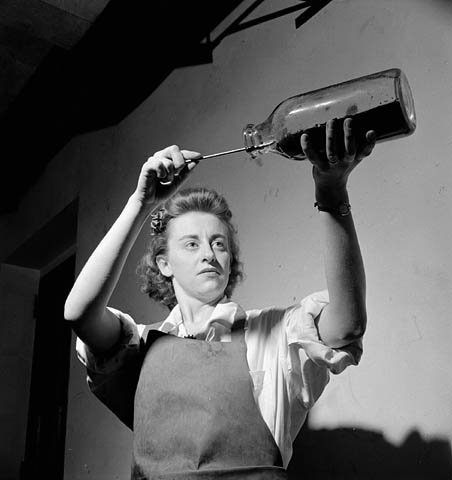  Women worker poses emptying a bottle containing penicillin mold during penicillin production at the Connaught Labs 