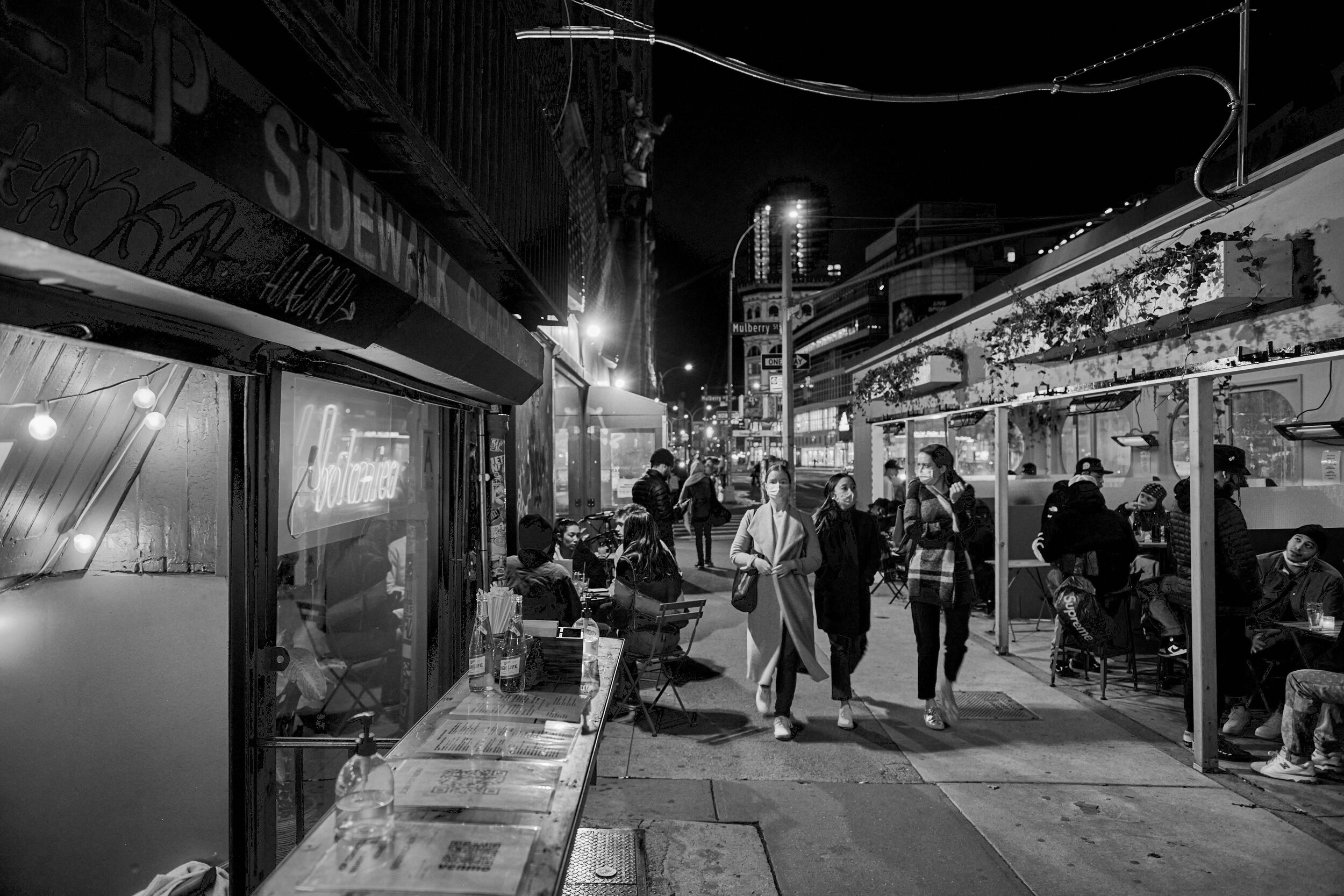 Black and white photo of outdoor seating area and sidewalk seating at night