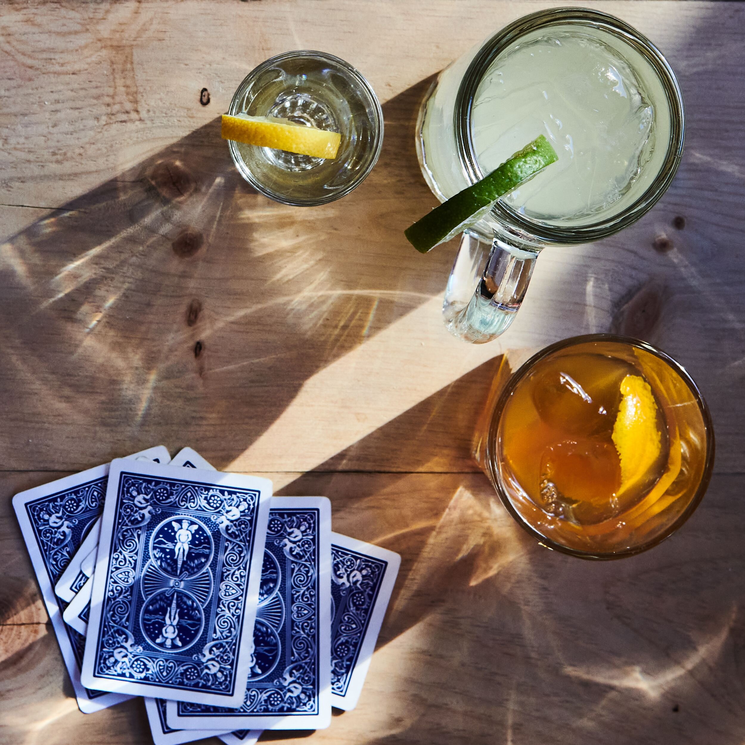 Several drinks on a table with playing cards