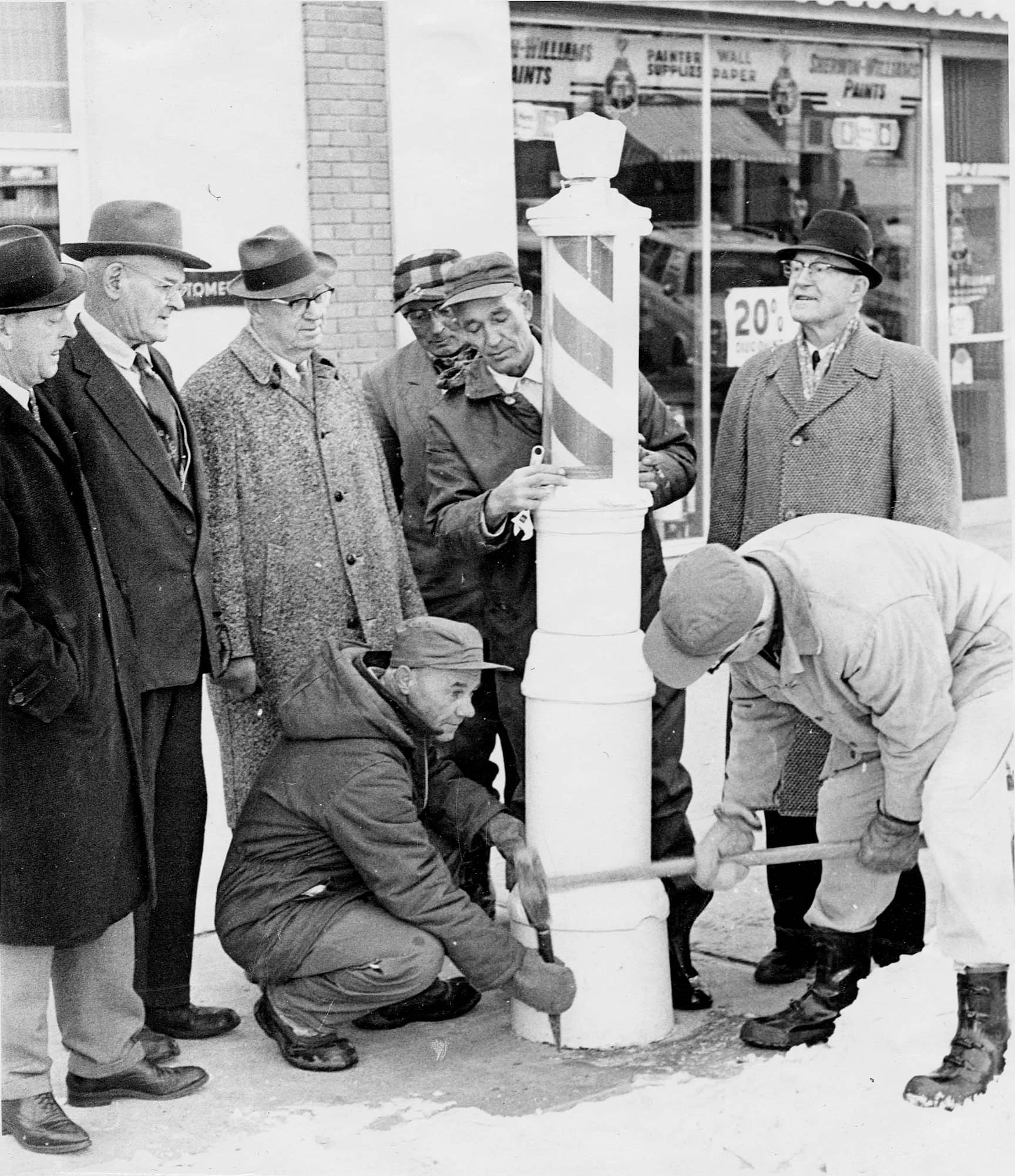 Caption from the Lethbridge Herald November 29, 1965: “SAVING BARBER POLE FOR POSTERITY ~ When the late James and Harold Westbrook put this barber pole in place on 6th St. S. some 40 years ago they probably never dreamed it would end up in the Lethbridge and District Museum. But sidewalk barber poles are relics of the past and this one from the Westbrook Barber Shop is believed to be one of the last in the nation. Left to right are R.E. (Bob) Faulds, present owner of the shop; Andrew Staysko and Chris Gibson, museum officials; city employees Nick Poneck (immediately behind the pole); John Lanning (kneeling with chisel) and Charles Kunz (with hammer); and George McKillop, also of the museum.” Photo courtesy the Galt Museum & Archives: 19730307000