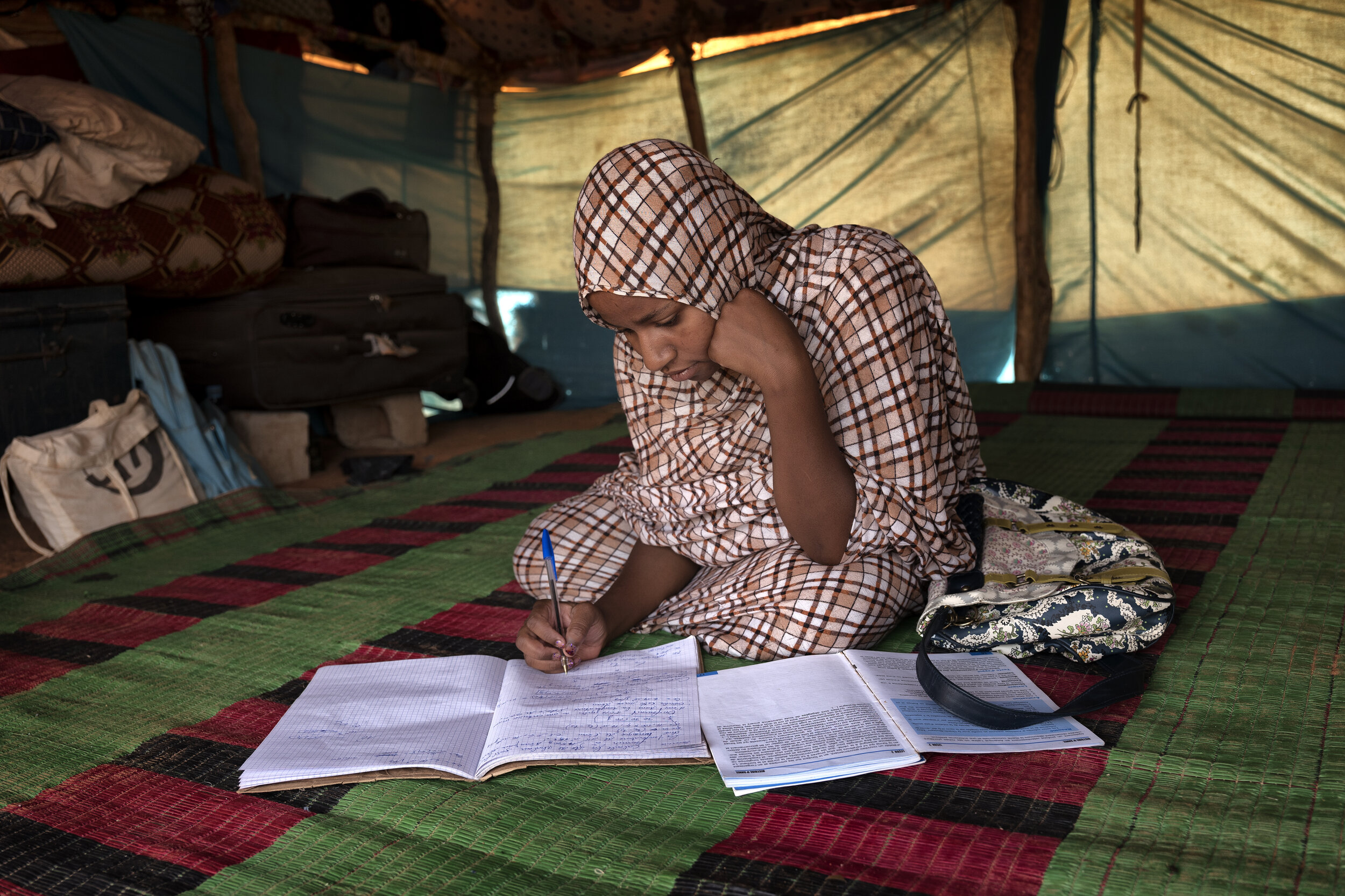 Tinalbarka, a refugee from Mali, does schoolwork inside her family’s tent in Mbera refugee camp, Mauritania, April 14, 2016.