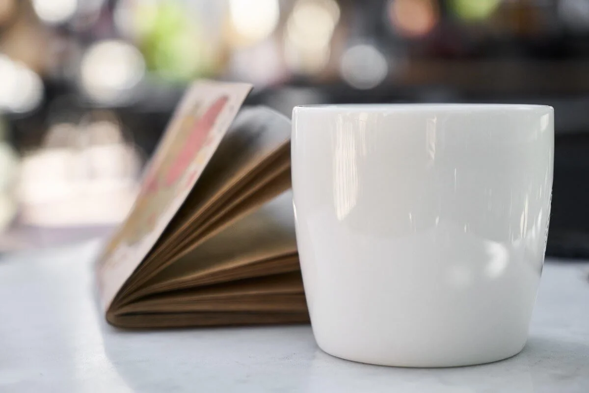 Close-up of a coffee cup and open notebook on a table, symbolizing focus and planning for using an AGI calculator to manage taxes and finances.