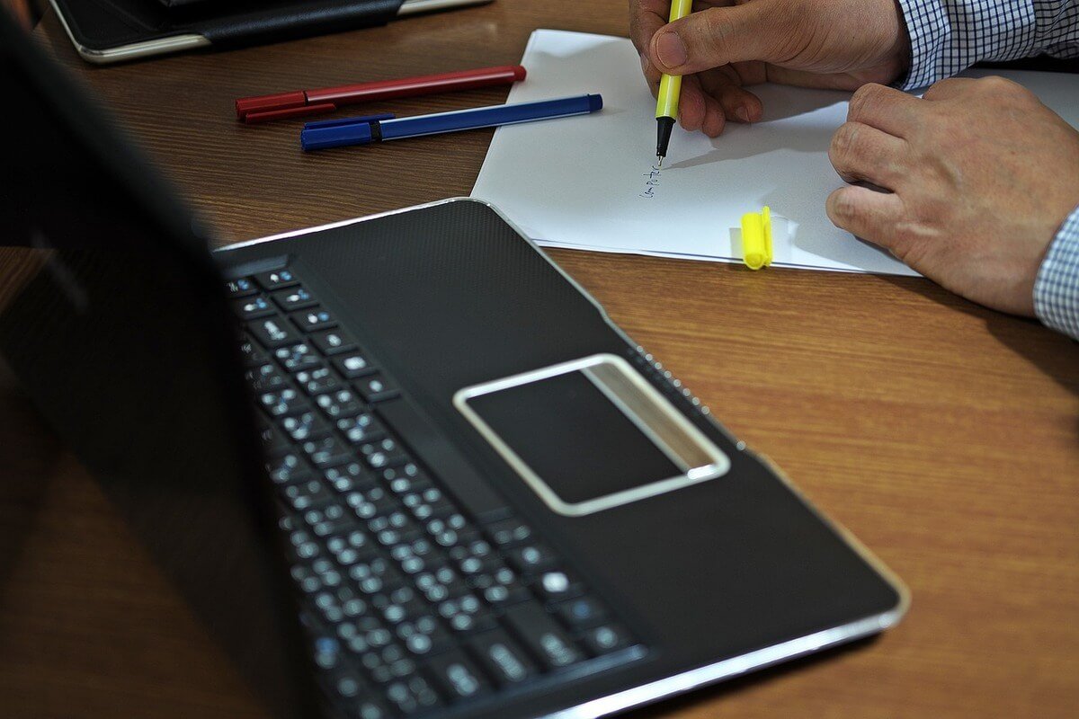 Person working at a desk with a laptop and documents, representing the process of receiving a tax refund to show in bank.