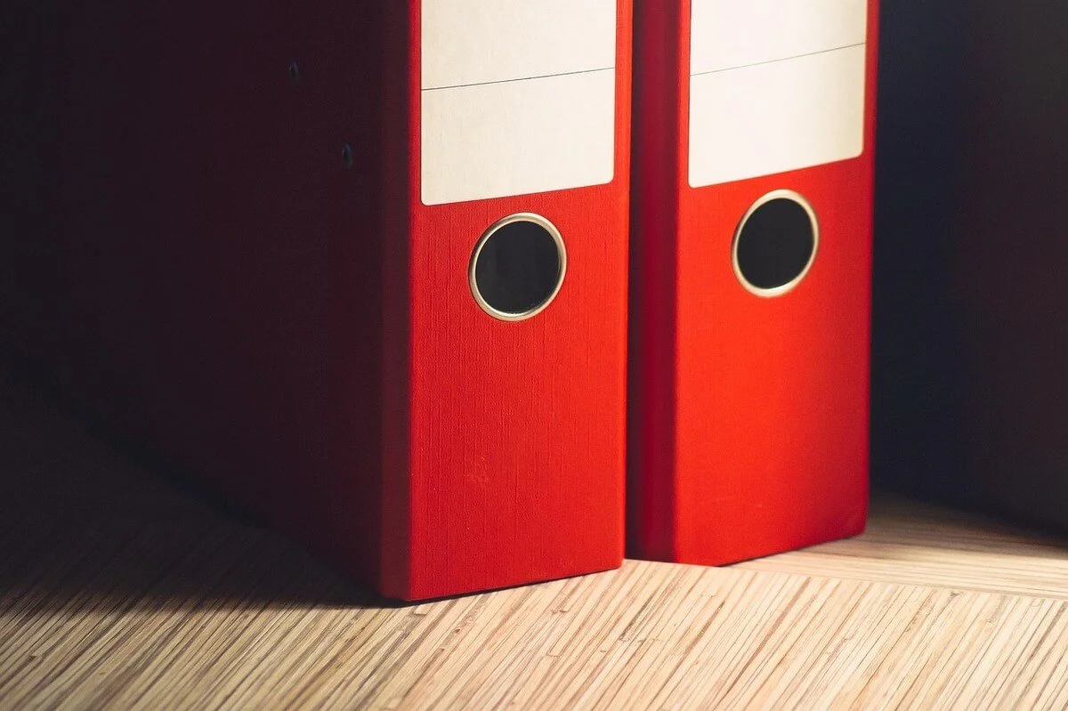 Two red binders on a wooden surface representing financial records and the question, is Trump getting rid of income tax.