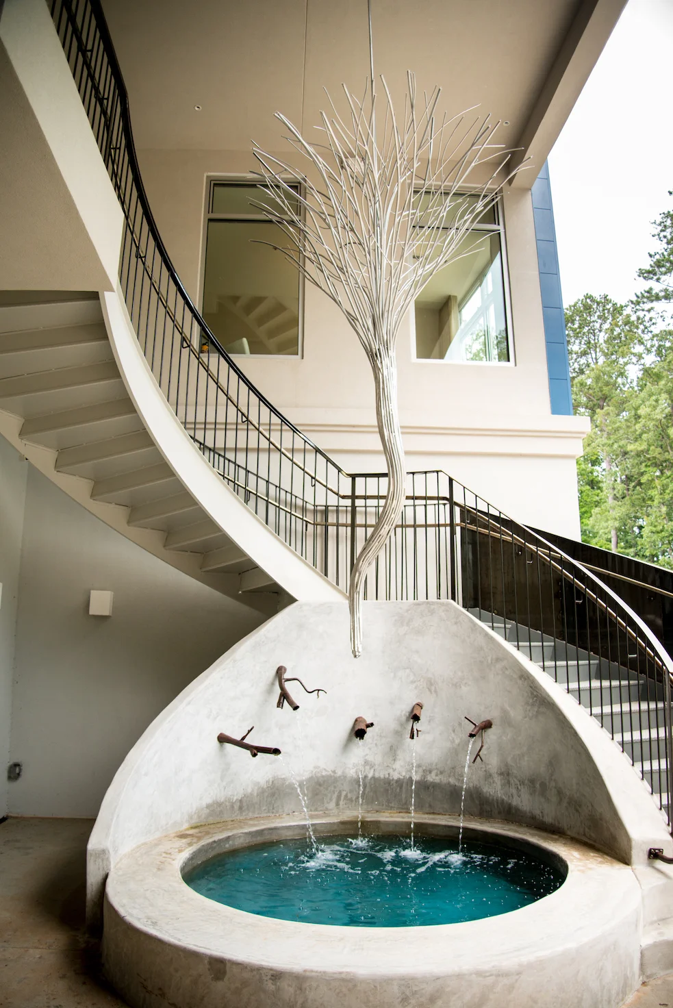 Robert Rausch designed the light fixture that hangs above a fountain alongside the staircase fabricated by Gault Designs. Photo by Mia Yakel.