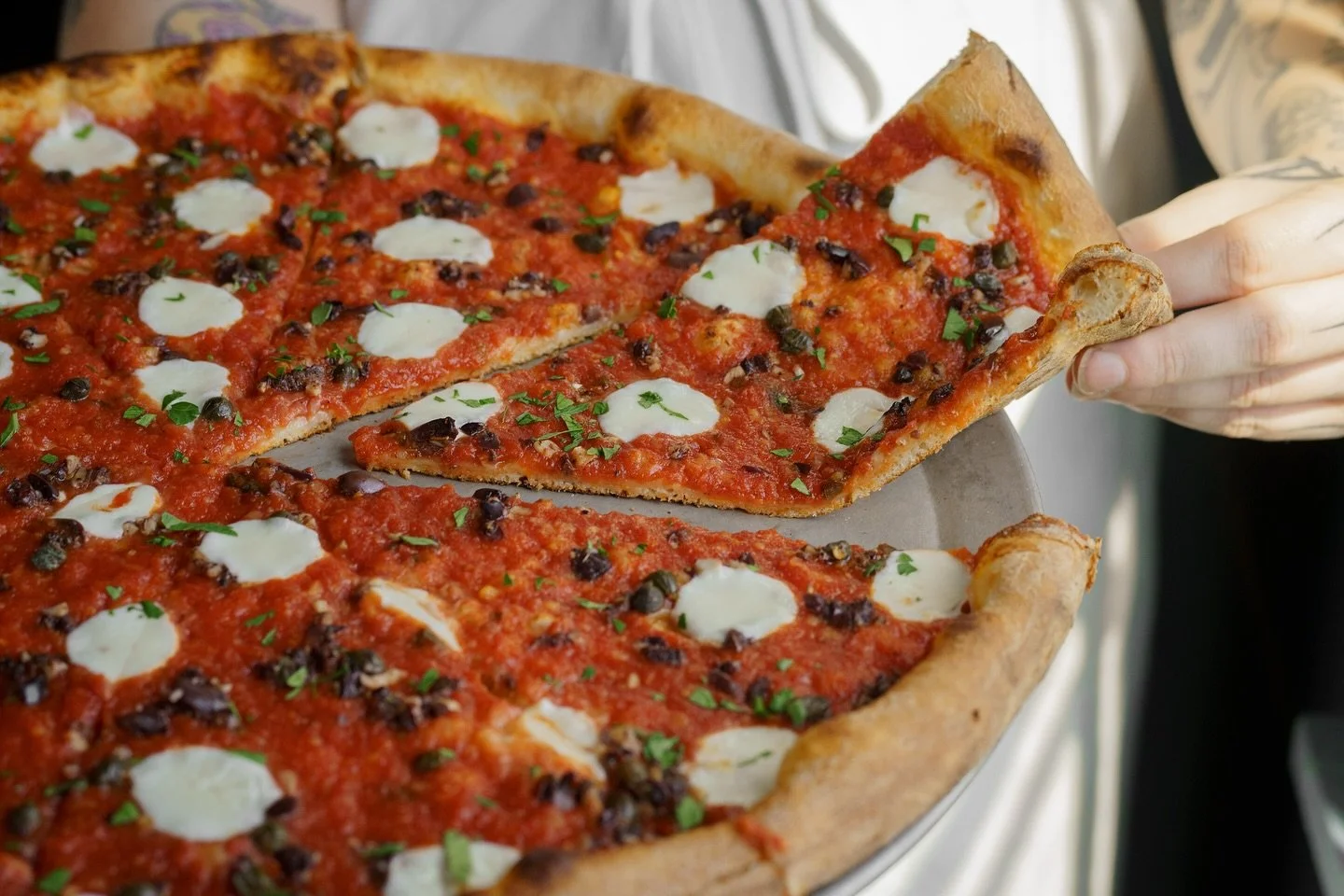 Say hello to The Working Lady🍕 Red sauce, fresh mozzarella, asiago, and a bold puttanesca mix finished with fresh parsley. The puttanesca brings a rich, briny depth that makes this pie truly stand out. Available at all locations!