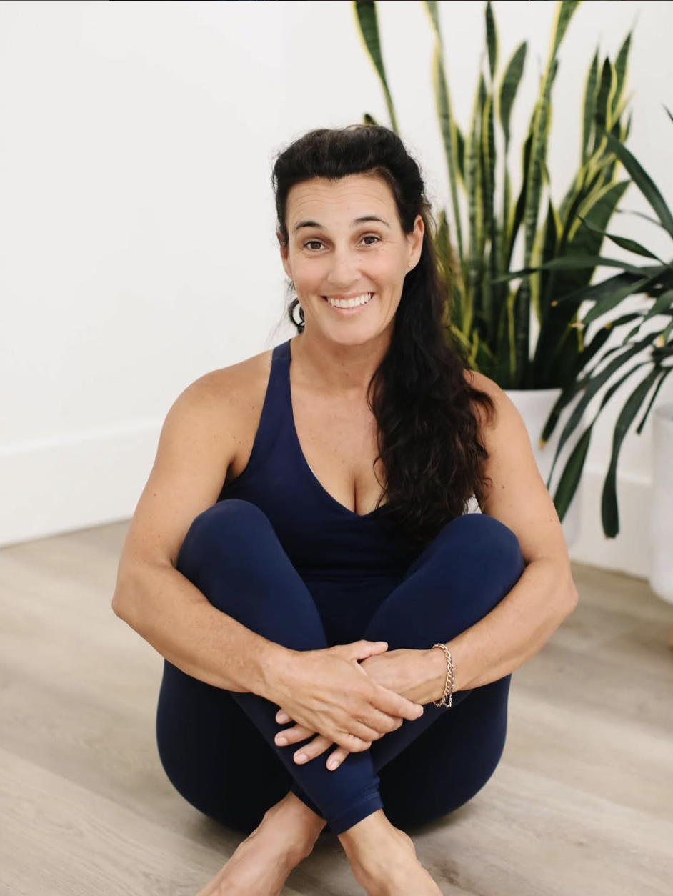 Vanessa Lyons seated on a yoga studio floor, smiling