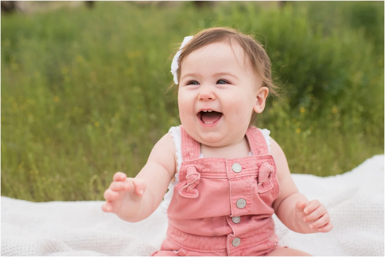 Baby girl laughing in a field of tall grass