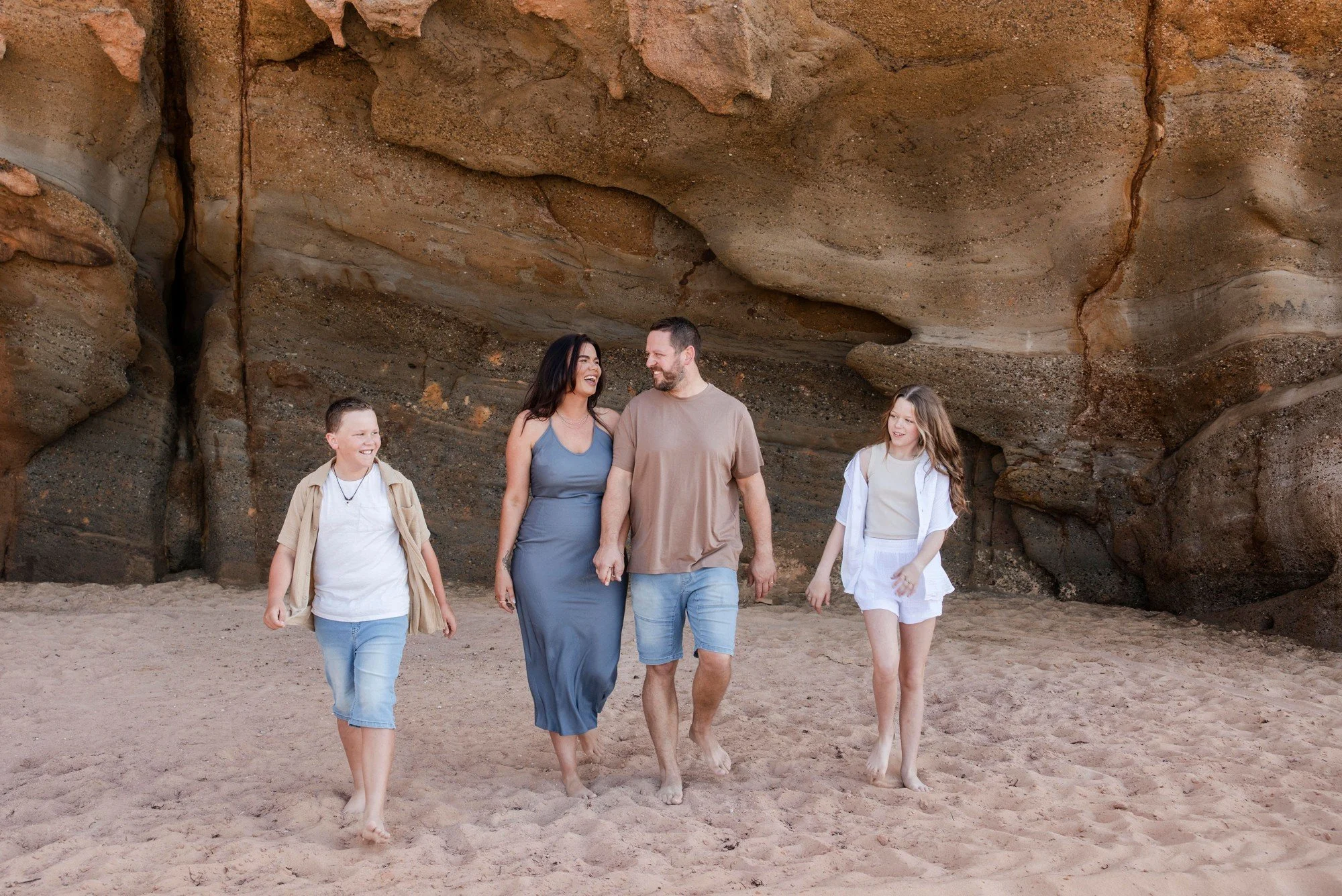 Family walking together across the beach under sandstone cliffs