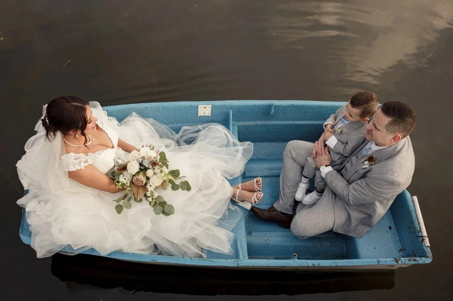 Bride and groom relaxing in a blue rowboat, photographed from above