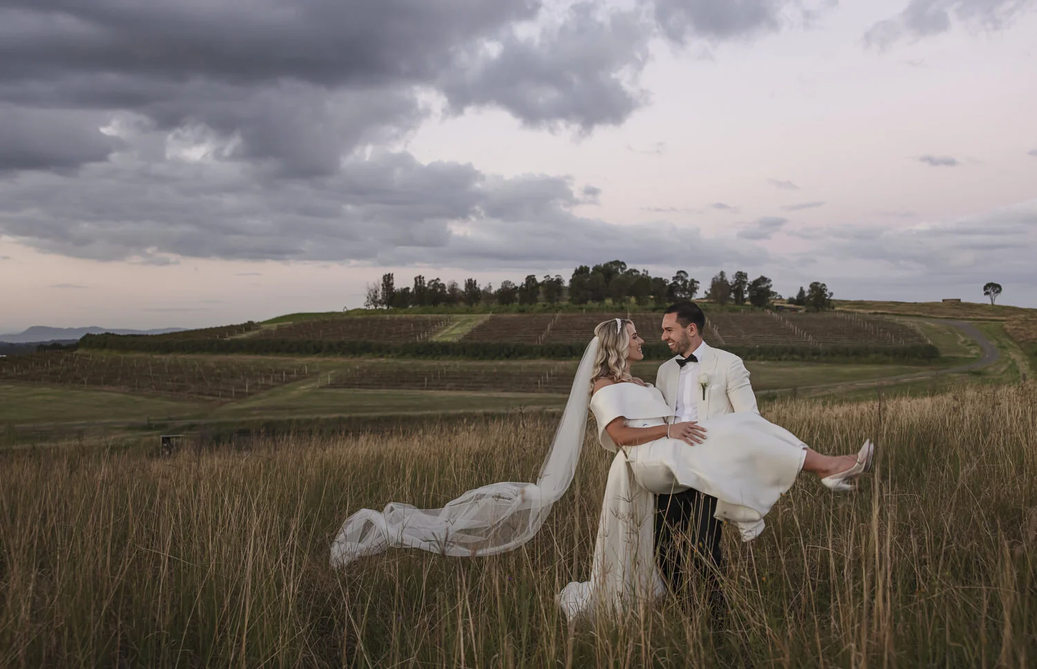 Newlyweds walking through Peterson House vineyard rows
