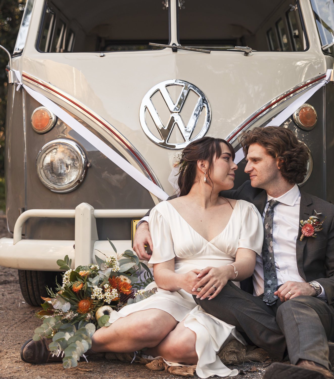 Couple laughing as they sit against a vintage VW Kombi at a Newcastle wedding