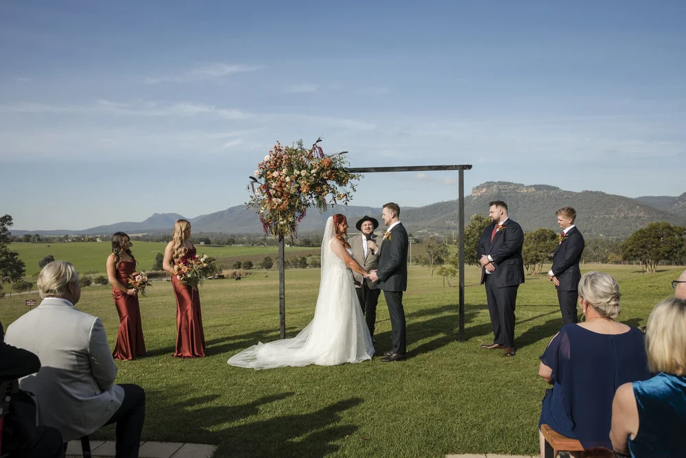 Couple at a floral arbour on The Lawn with the mountains behind, Adams Peak Country Estate, Broke