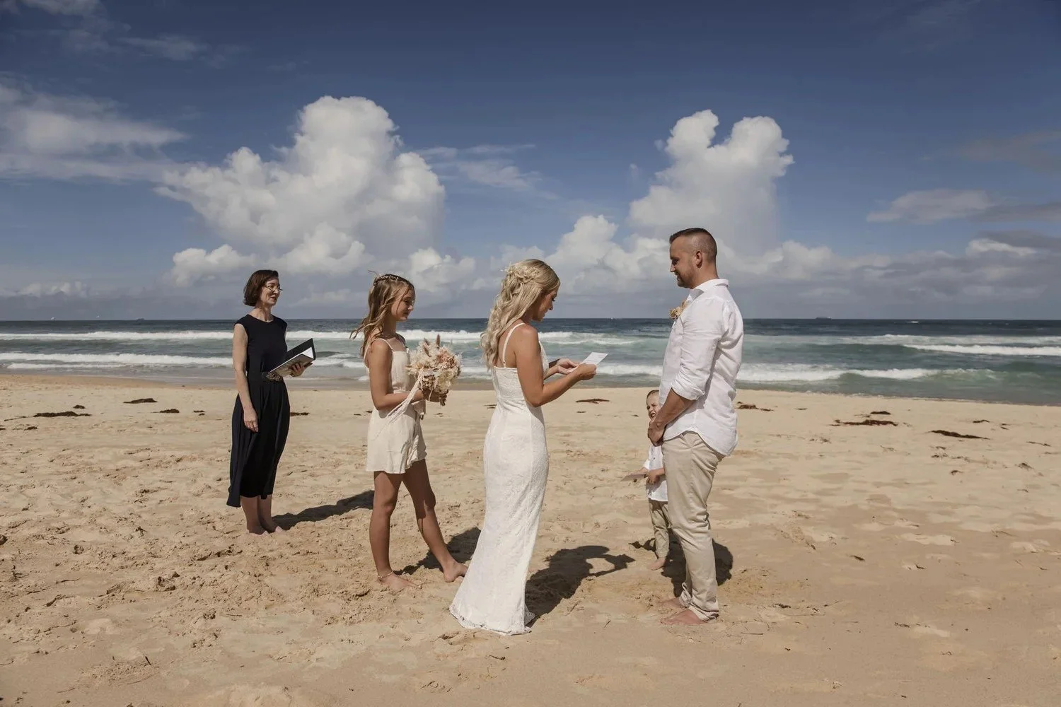Small beach ceremony on the sand at Caves Beach with a celebrant and family