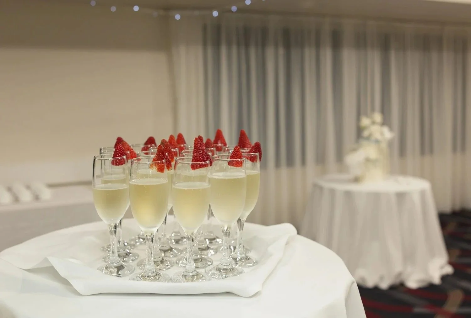 Glasses of sparkling wine topped with strawberries on a reception table