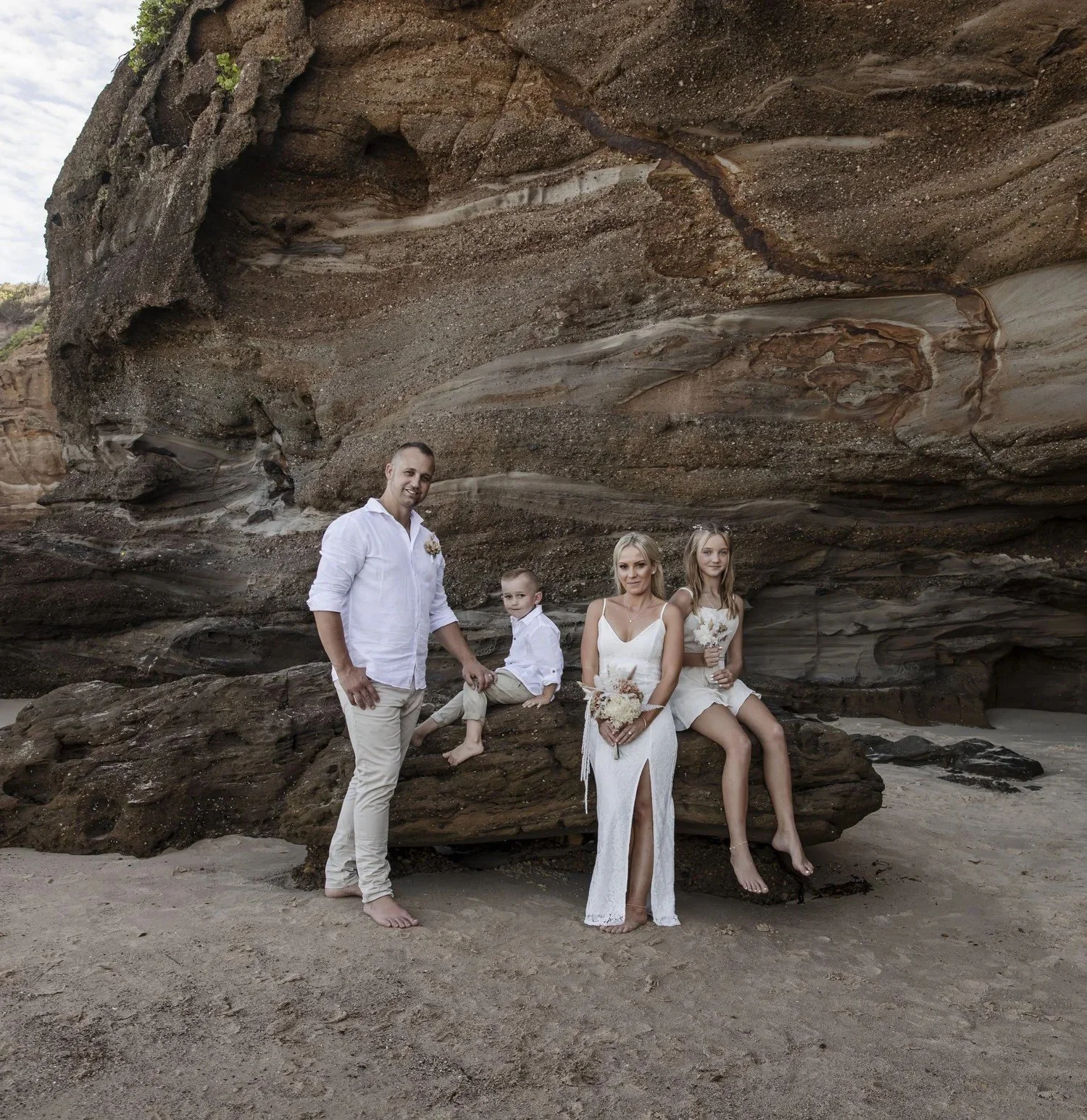 Family portrait against the layered sandstone cliffs at Caves Beach