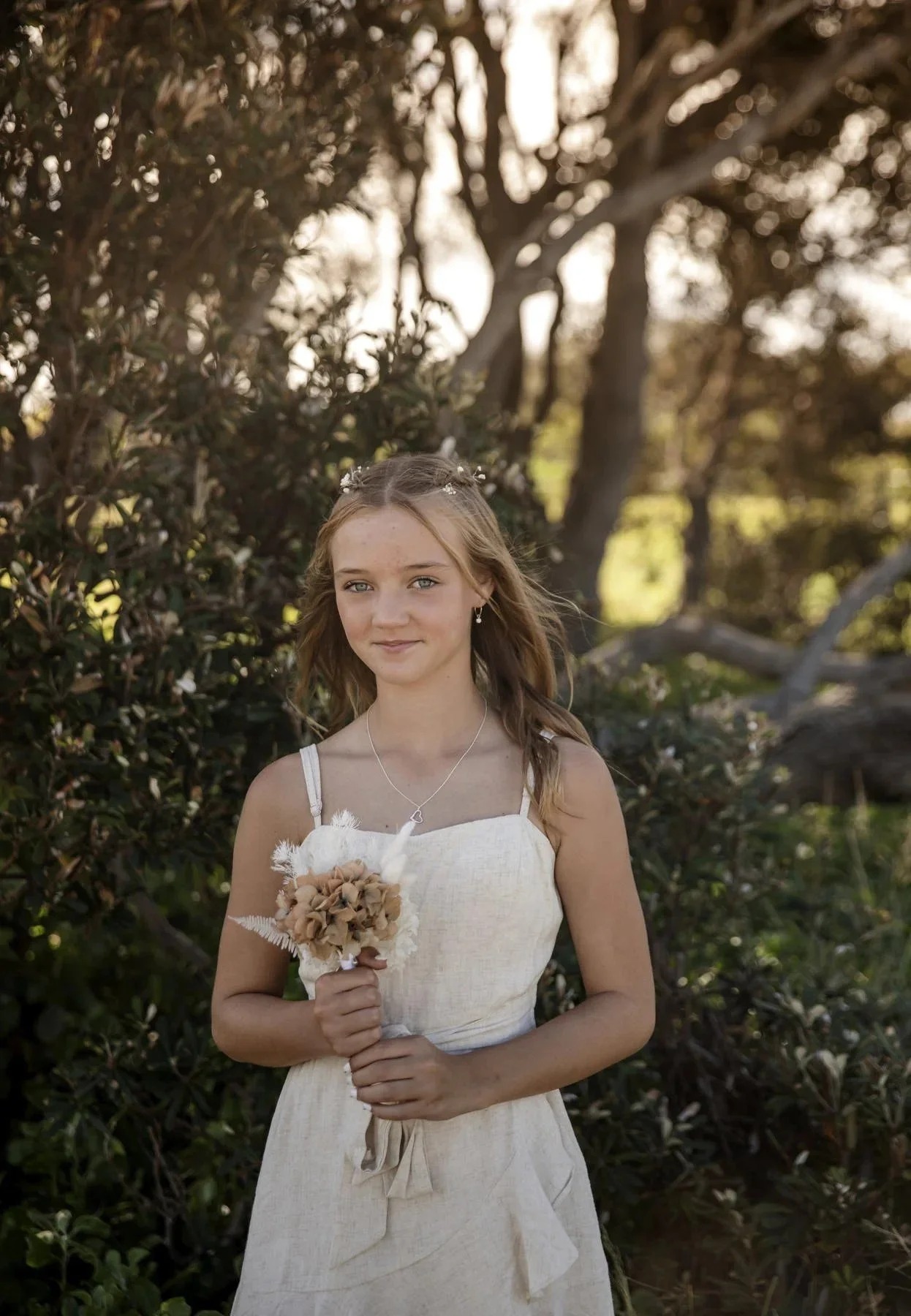 Girl holding a dried flower posy among coastal trees
