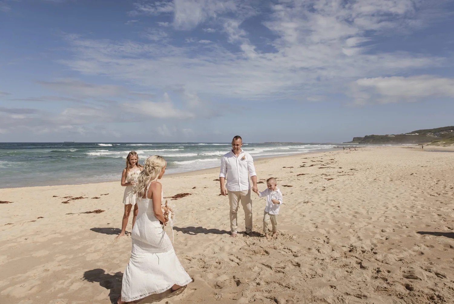 Bride walking along the beach towards the ceremony with the surf behind