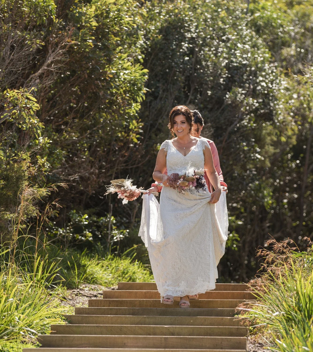 Bride walking down timber steps through coastal greenery to her clifftop ceremony
