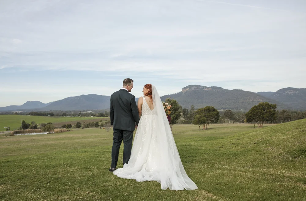 Couple standing in open paddocks looking out to the Brokenback Range, Adams Peak Country Estate, Broke