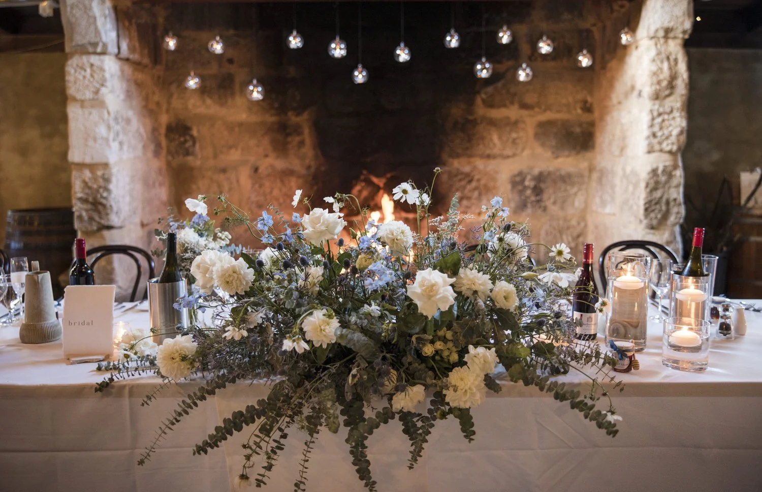 flowers on bridal table in front of fireplace at Peppers Creek Barrel Room  