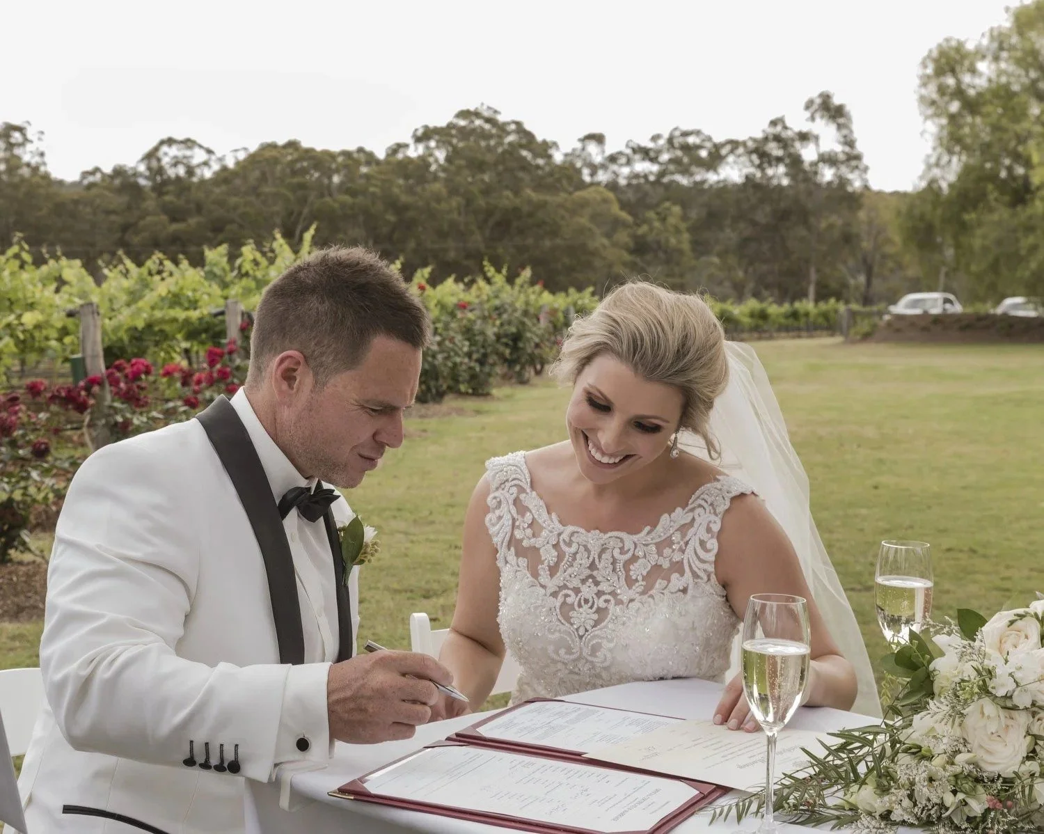 Couple signing the register in front of the vines and roses, Spicers Vineyards Estate, Pokolbin