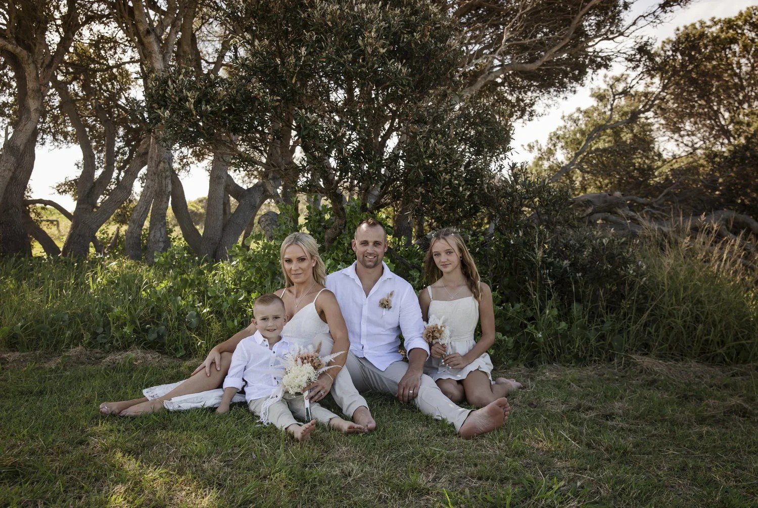 Relaxed family portrait under the coastal trees above Caves Beach