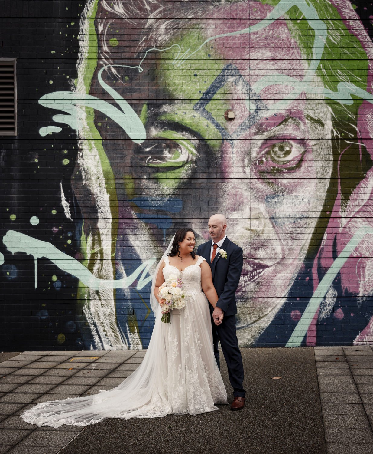 Bride and groom in front of a large, colourful street-art mural