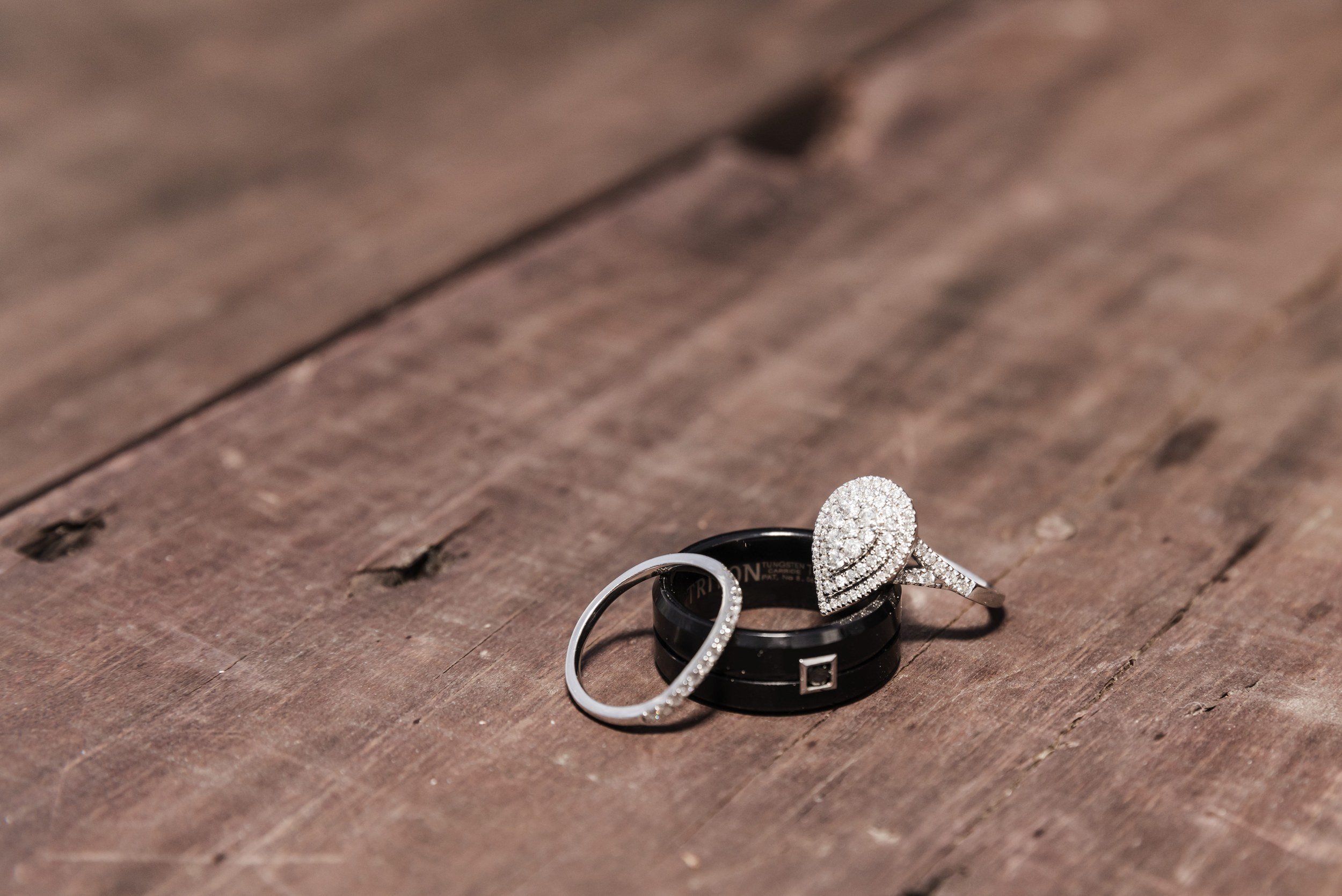 Engagement ring and two wedding bands resting on weathered timber