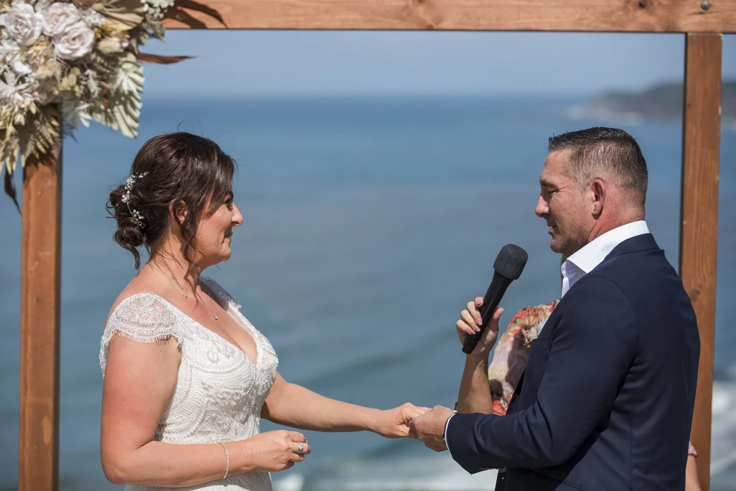 Groom reading his vows with the blue ocean behind him