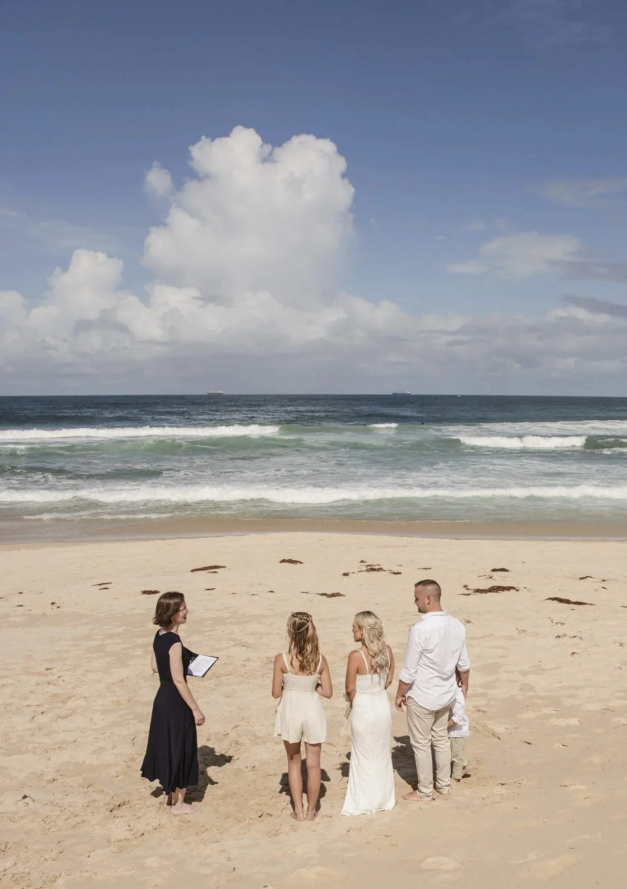 Small beach ceremony on the sand at Caves Beach with a celebrant and family