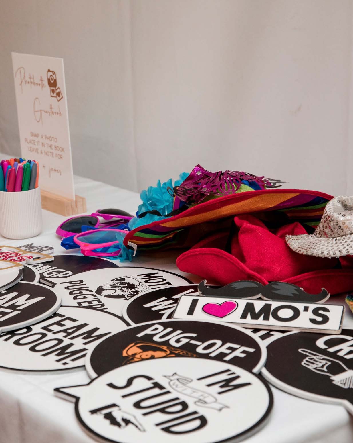 Photo booth props including hats, signs with humorous messages, and colorful accessories on a table.