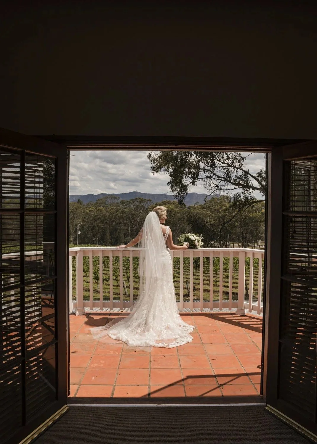 Bride on the verandah framed by the doorway, valley view beyond, Spicers Vineyards Estate, Pokolbin