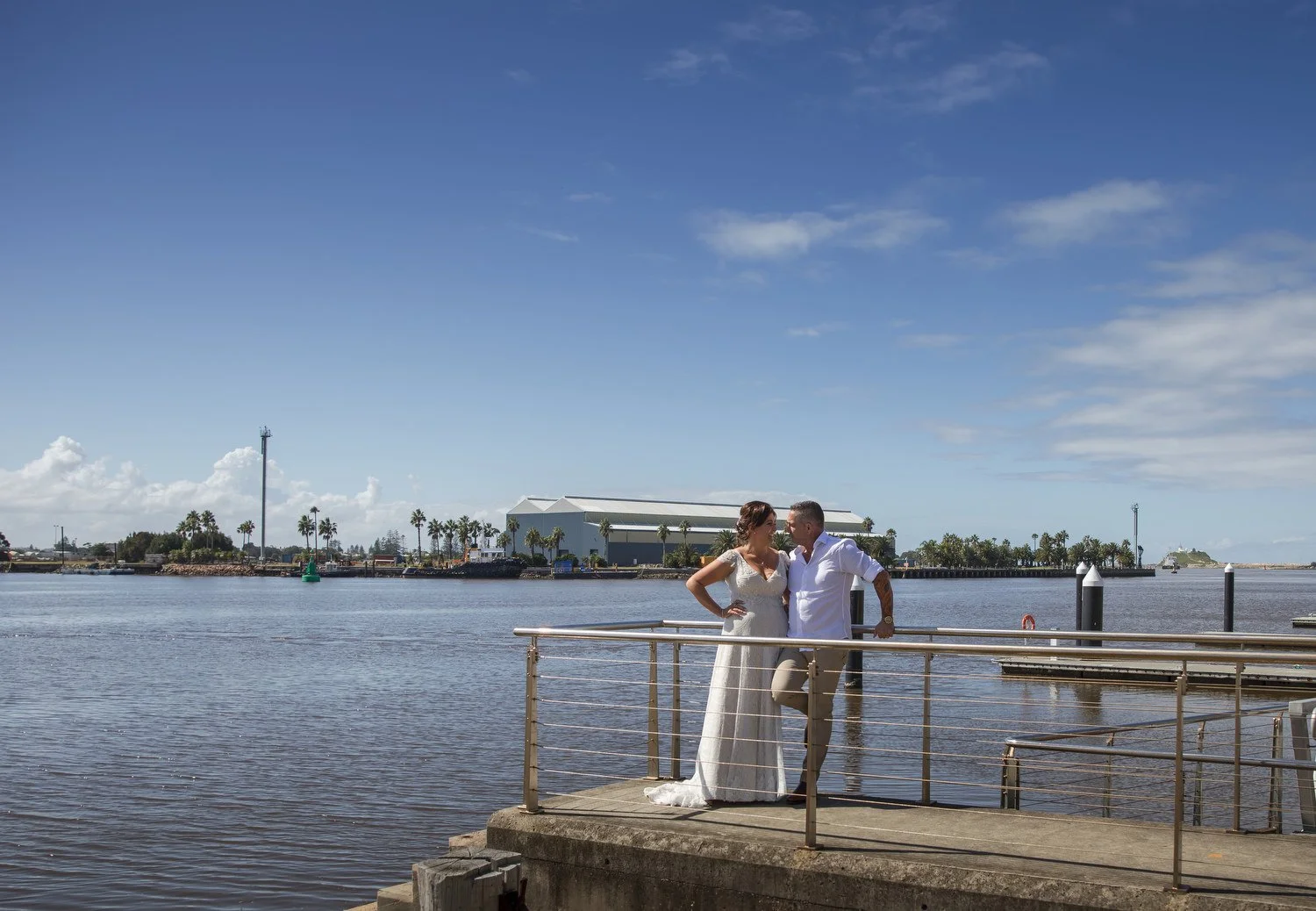Bride and groom on a harbour wharf under a big blue sky