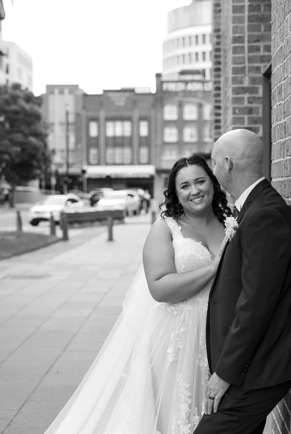 Black-and-white city-street portrait of a couple smiling at each other