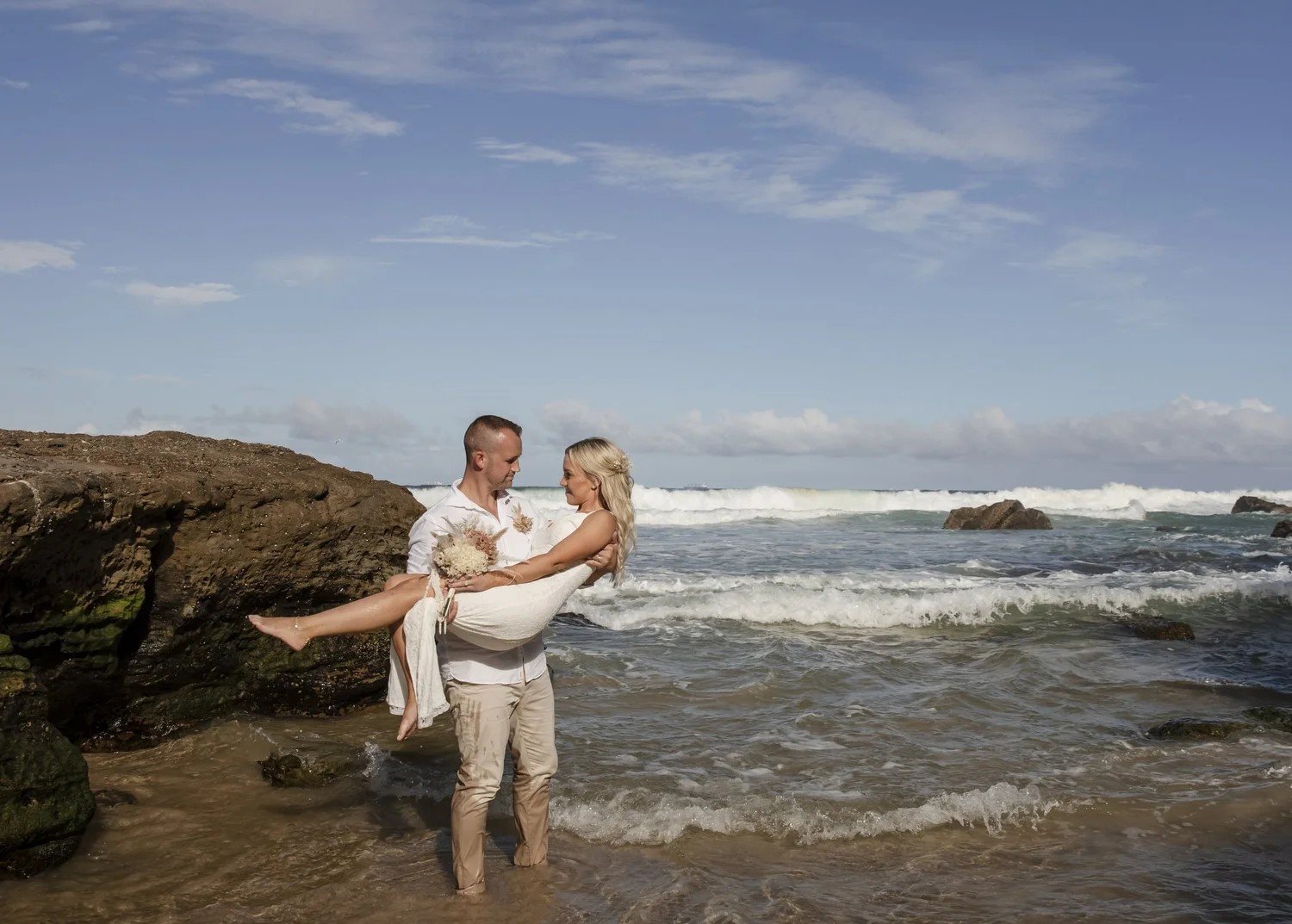Groom carrying the bride through the waves