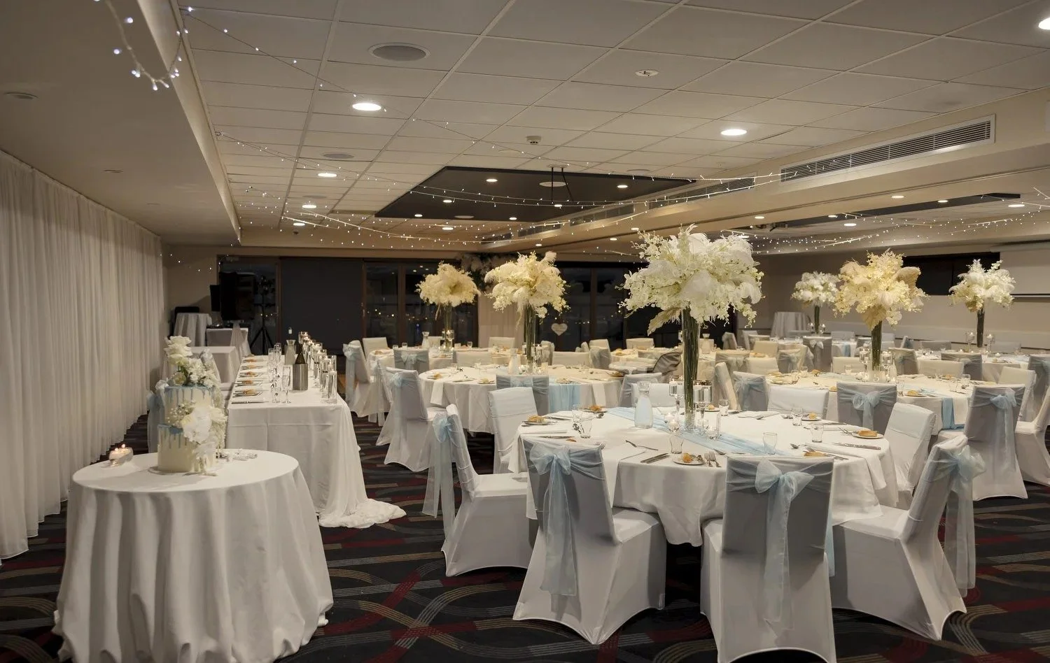 Reception room with round tables, white chair covers and floral centrepieces