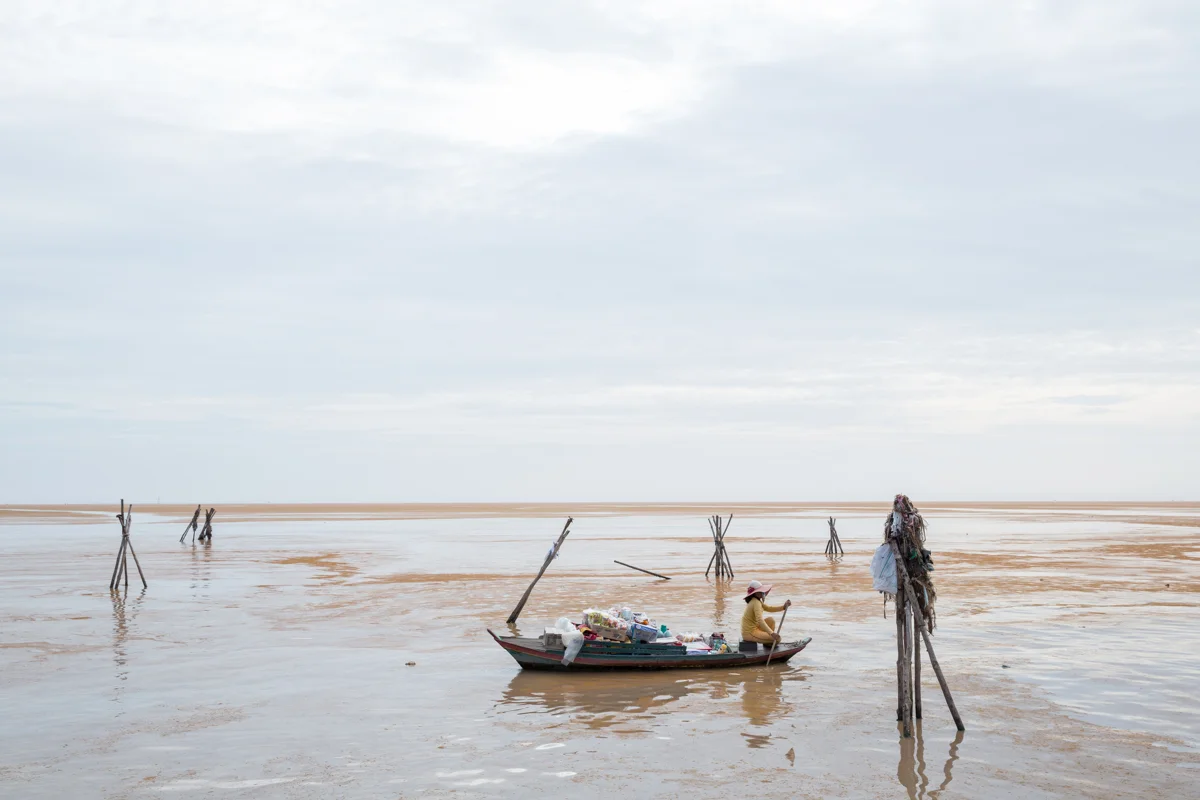 May 26, 2016 - Kampong Luang, Cambodia. A vendor paddles her boat on the outskirts of a floating village. The colour of the water on the lake changes seasonally. © Nicolas Axelrod / Ruom