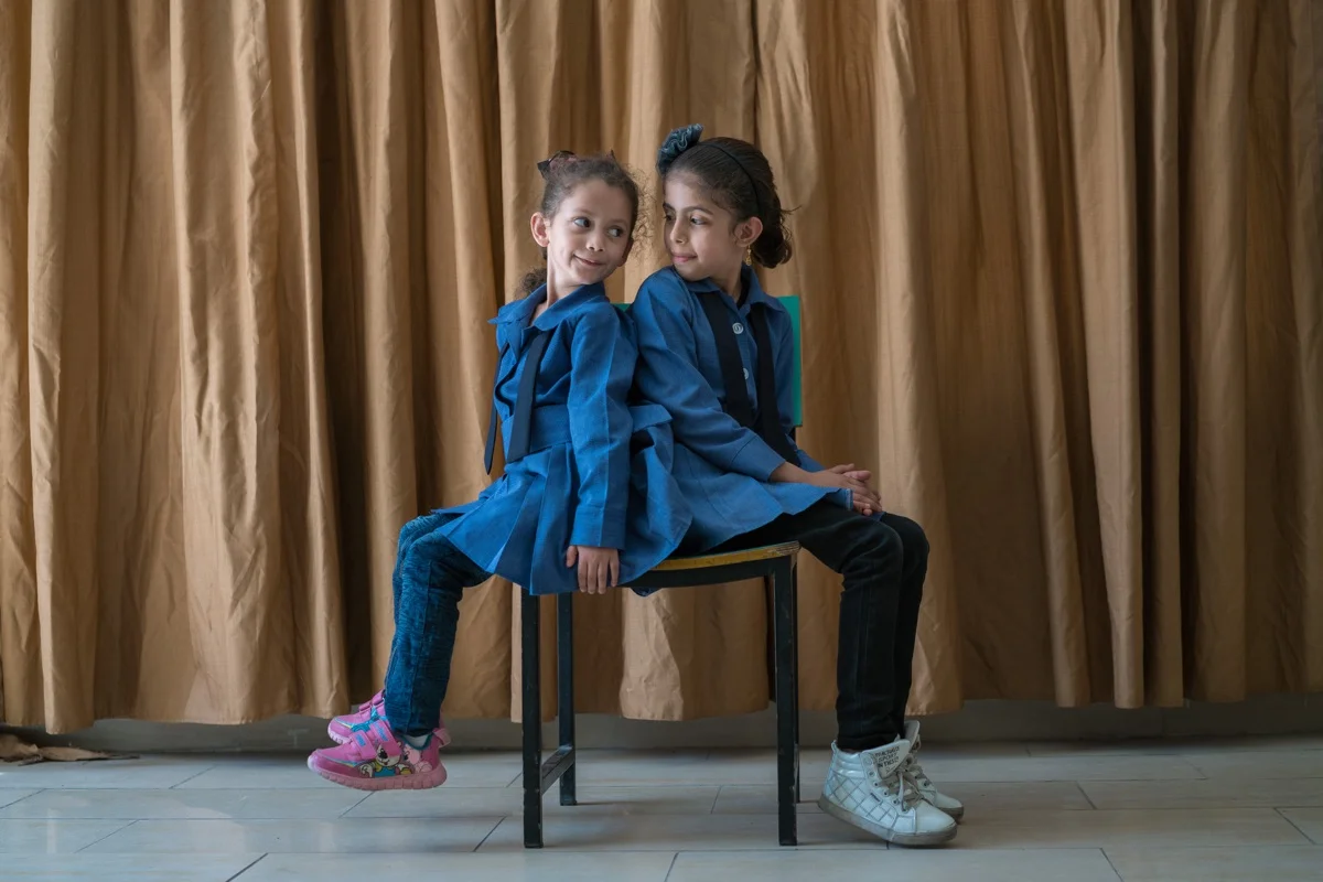AMMAN, JORDAN - OCTOBER 1, 2015: Maria (left) and her cousin Athari (right), are Syrian students at Khawla Bint Tha’laba Primary Girls School, a USAID-supported school located in an Amman suburb. They are one of around 65 Syrian students attending the USAID-supported school, which operates out of a rented building and struggles to accommodate the influx of refugees. In spite of the overcrowding, this school boasts a principal who is committed to accepting students, with one request for the parents: “Please bring a chair with you.” Overall in Jordan, around 128,000 new Syrian students are crowding already overburdened classrooms. Teachers, struggling to achieve basic levels of proficiency in their classes, have the added burden of trying to accommodate and integrate new students who have suffered unthinkable trauma and may need special counseling and care. USAID supports schools like this across Jordan by providing teacher training and by developing an early grade reading and math diagnostic tool. The agency also builds and refurbishes schools throughout the country.