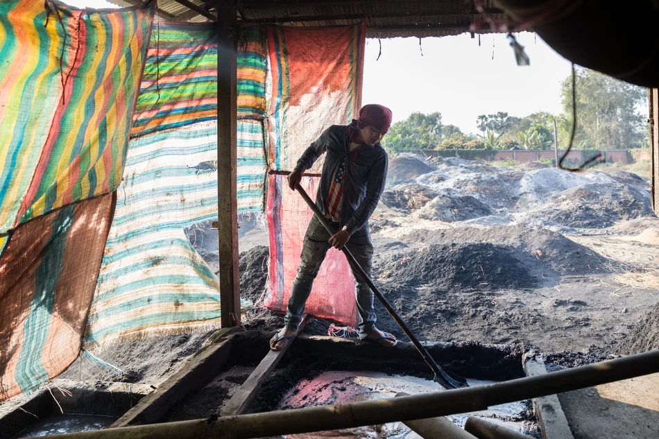 January 29, 2014 - Battambang, Cambodia. A man clears burn husks that come out of the water system. working gasifier. Rice milling - gasifier © Nicolas Axelrod / Ruom for SNV
