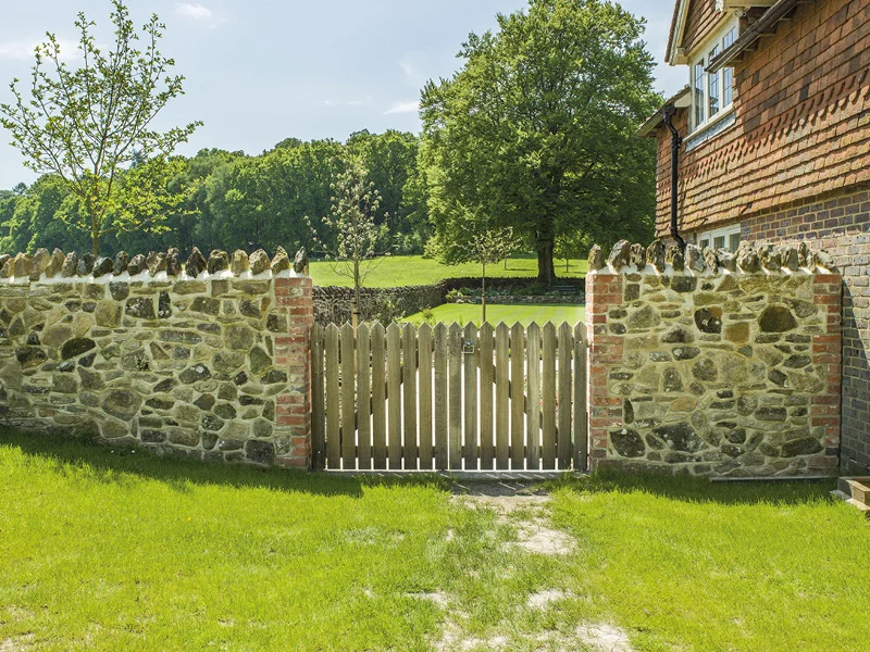Stone walling and bespoke gates provide security and rustic charm to the side of this property