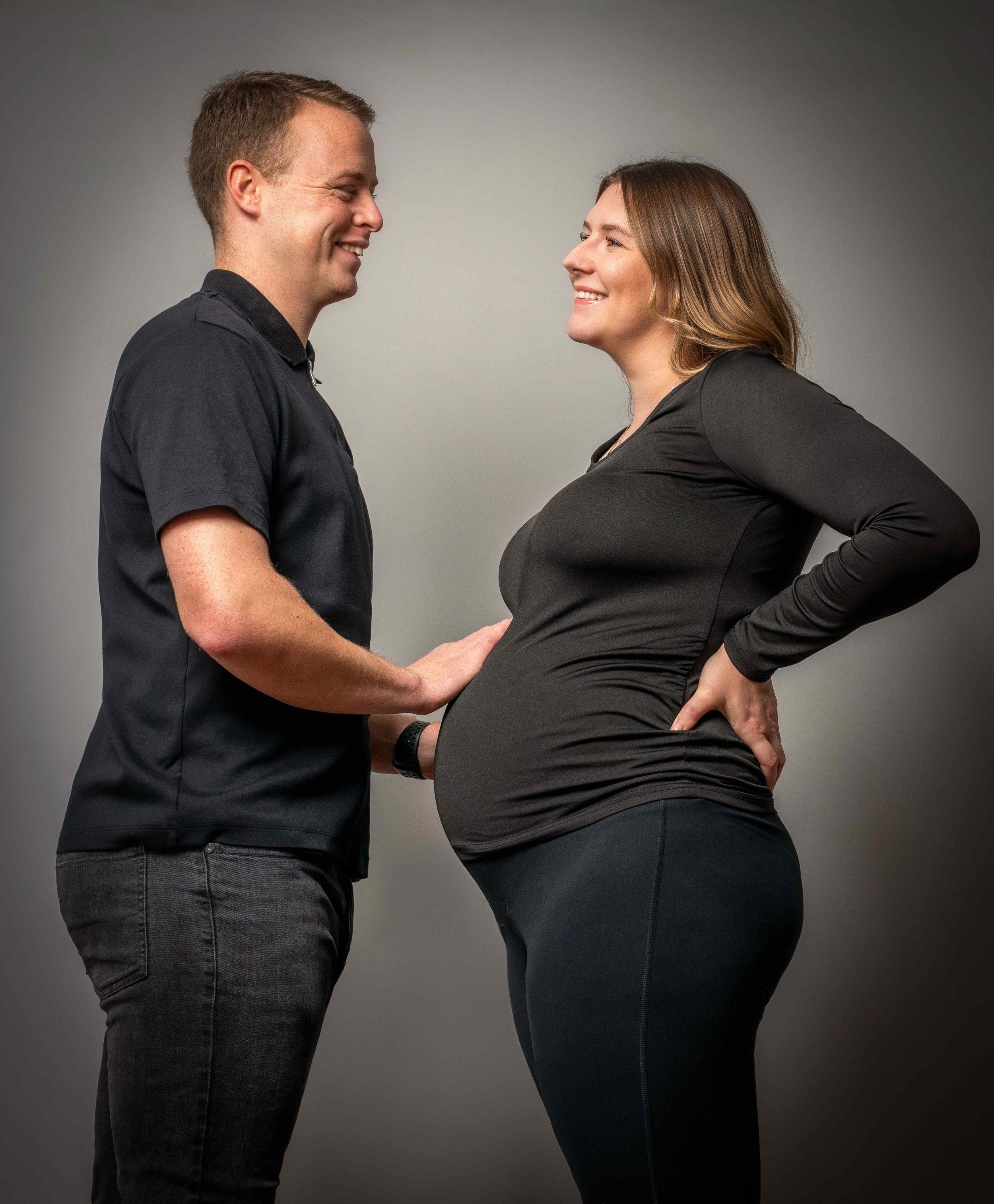 studio-maternity-portrait-couple-laughing-black-outfits.jpg