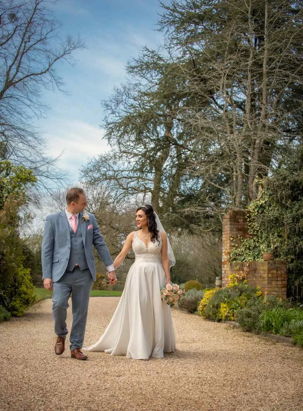 bride and groom walking hand in hand in the garden