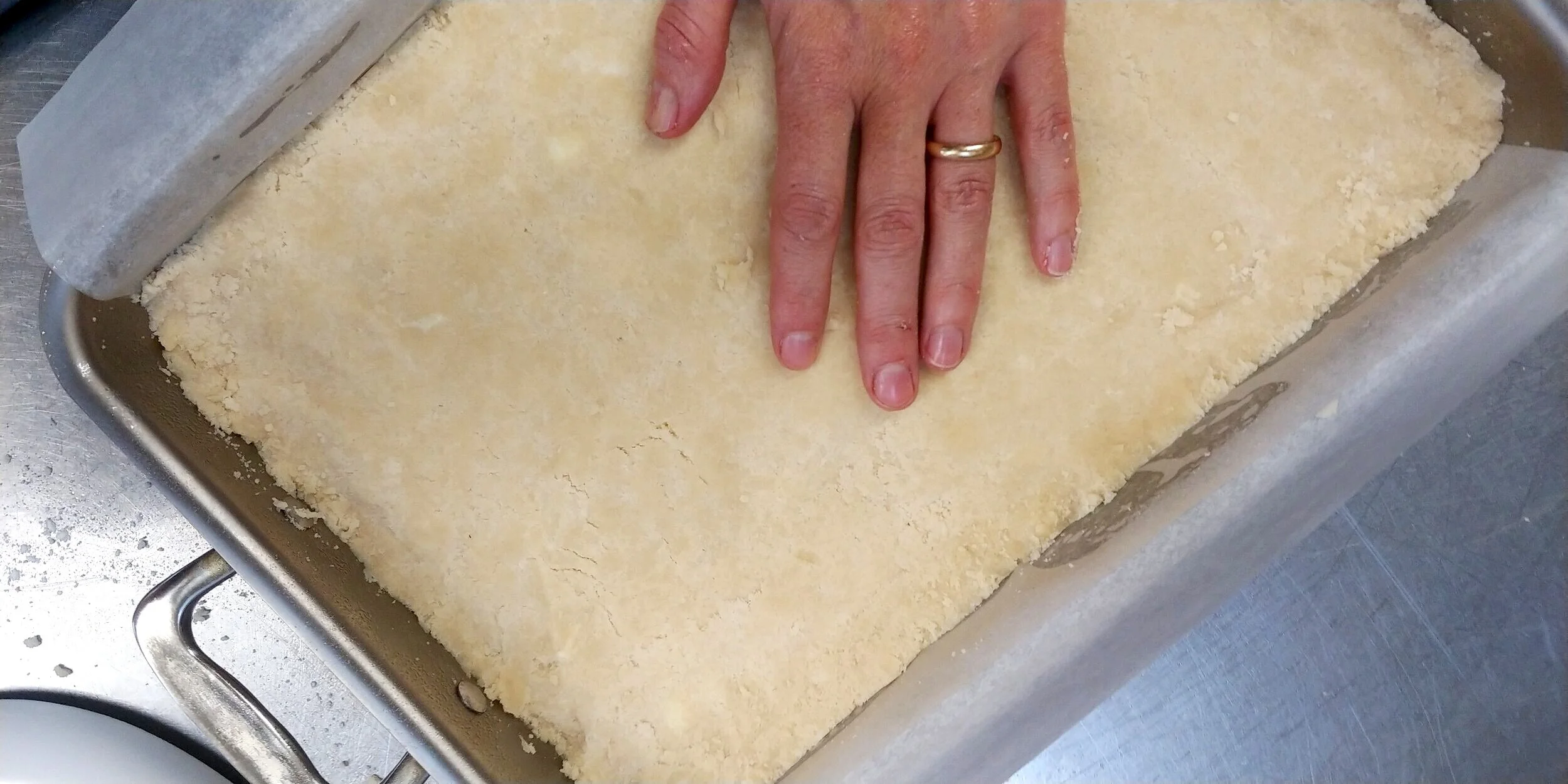 Press shortbread dough into prepared baking pan 360 Cookware baking pan is used in this recipe