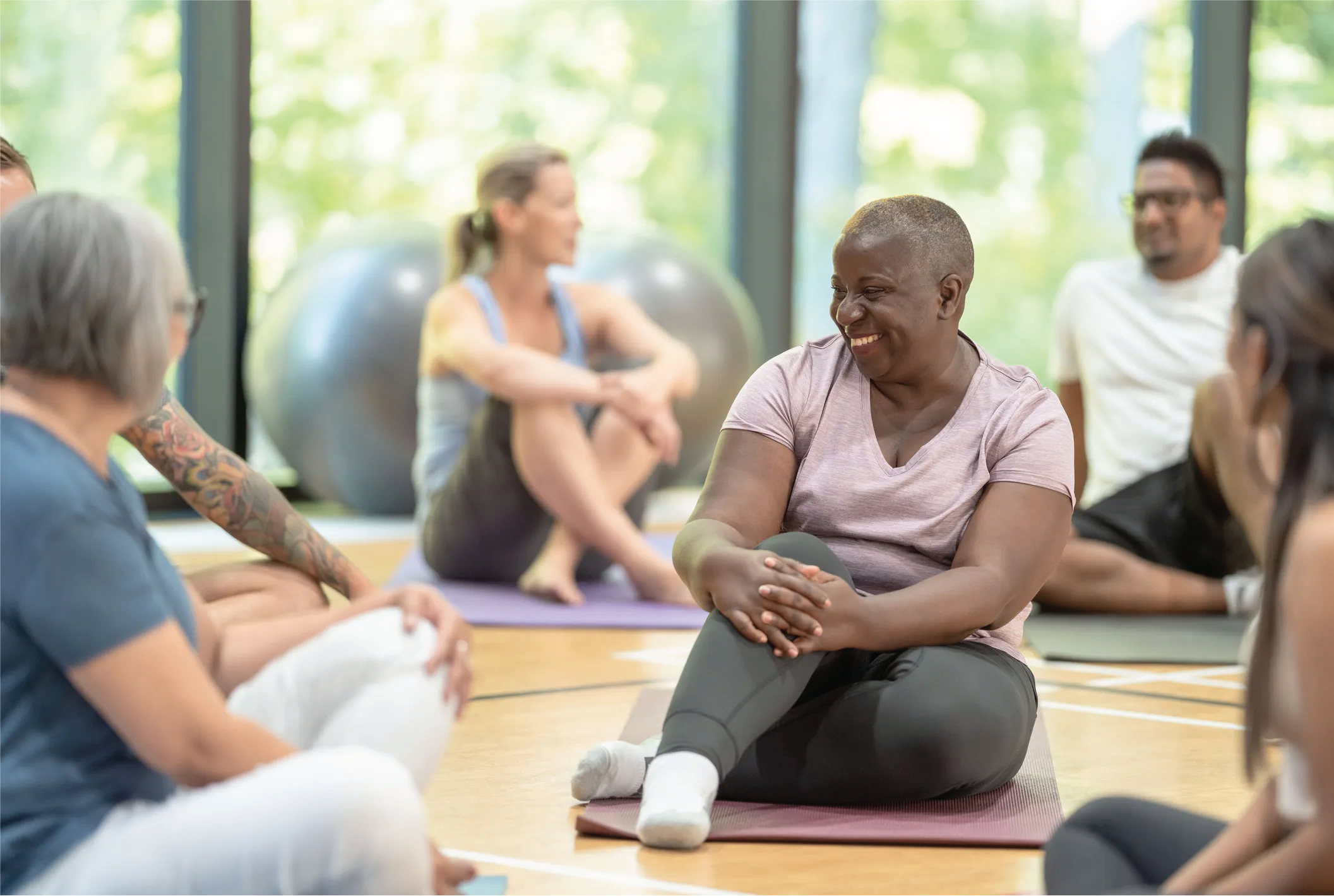 Senior women and men of different races sitting on yoga mats during a gentle yoga class.