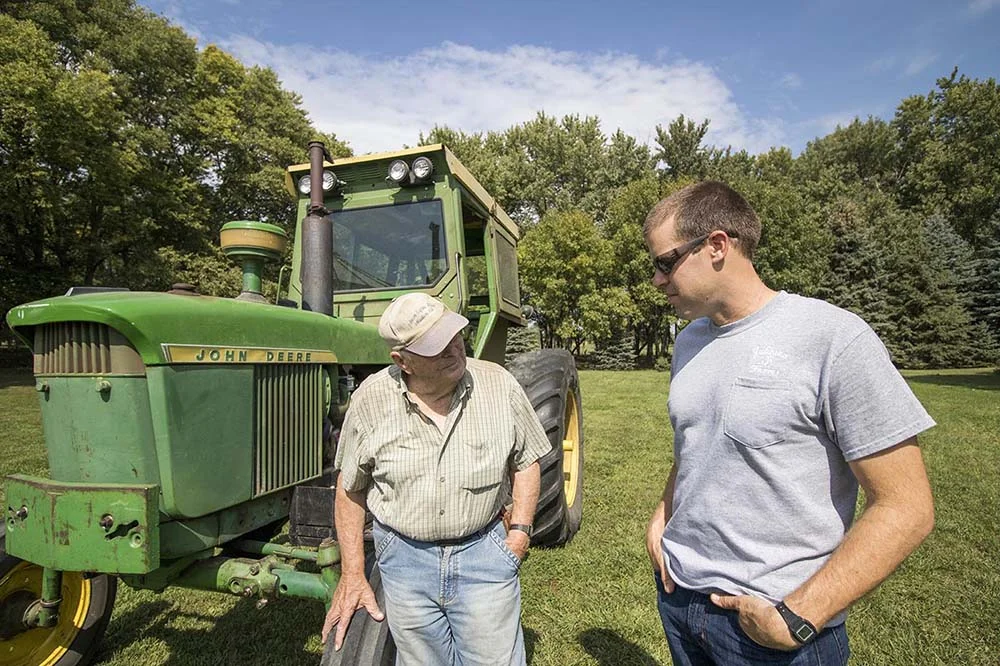   Aaron and his father, William, stand in front of their tractor.  