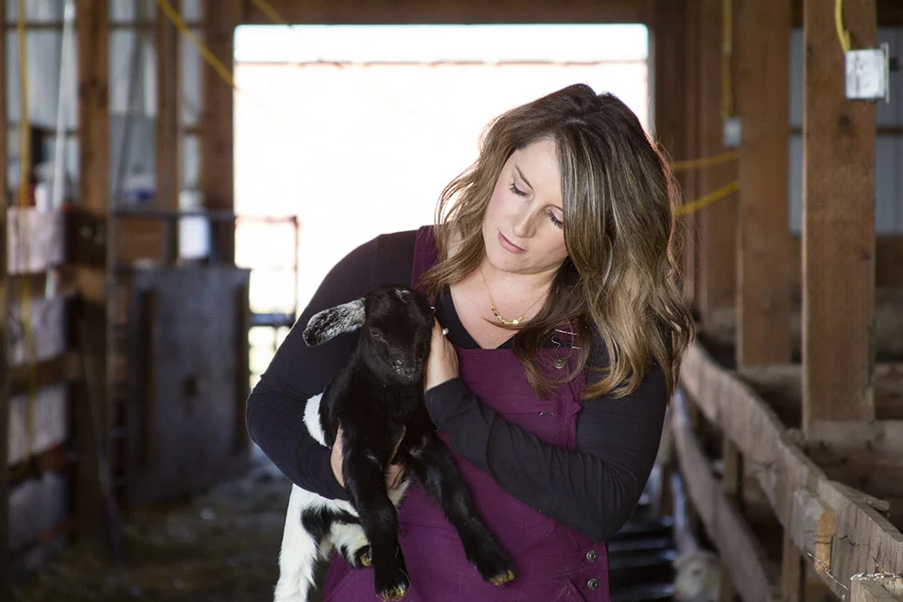 Sara holding a goat in the barn.