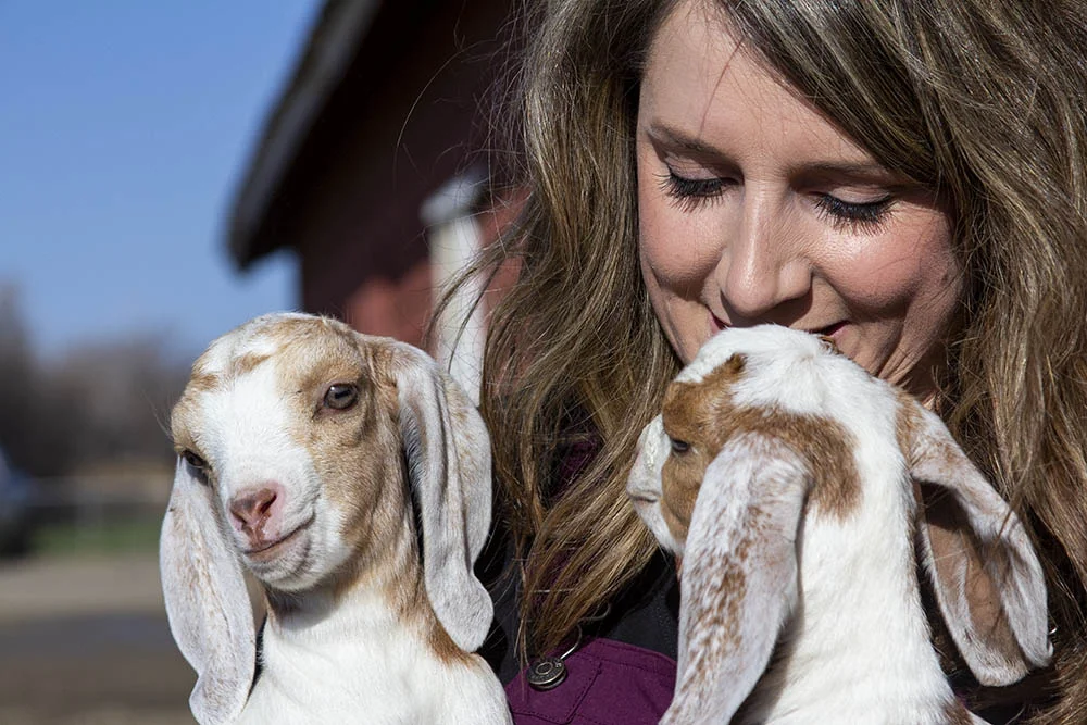 Sara snuggles with two goats at her home in Molt, Montana.