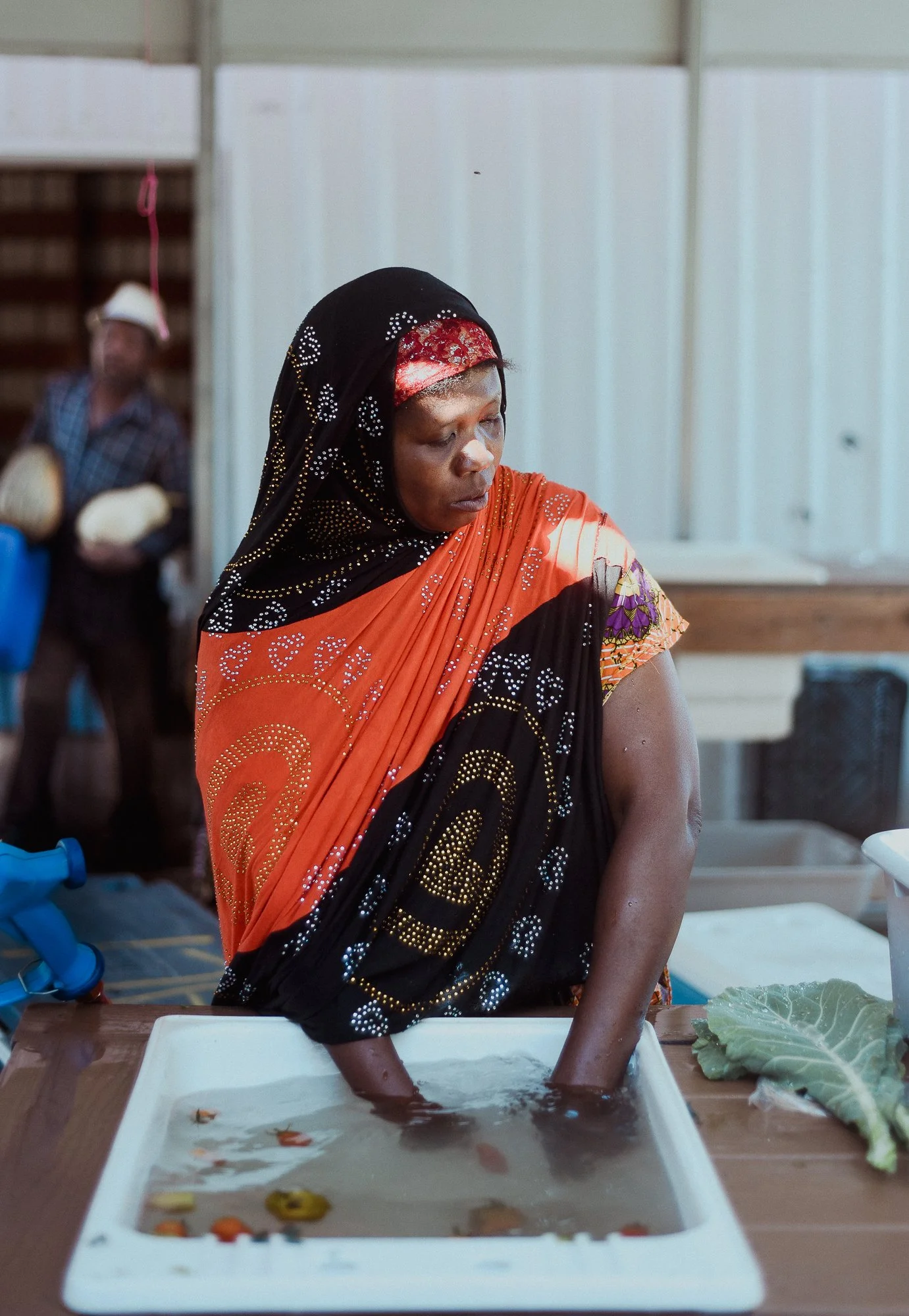    Khadija Mberwa washes tomatoes to prepare for the Boise Farmers Market   