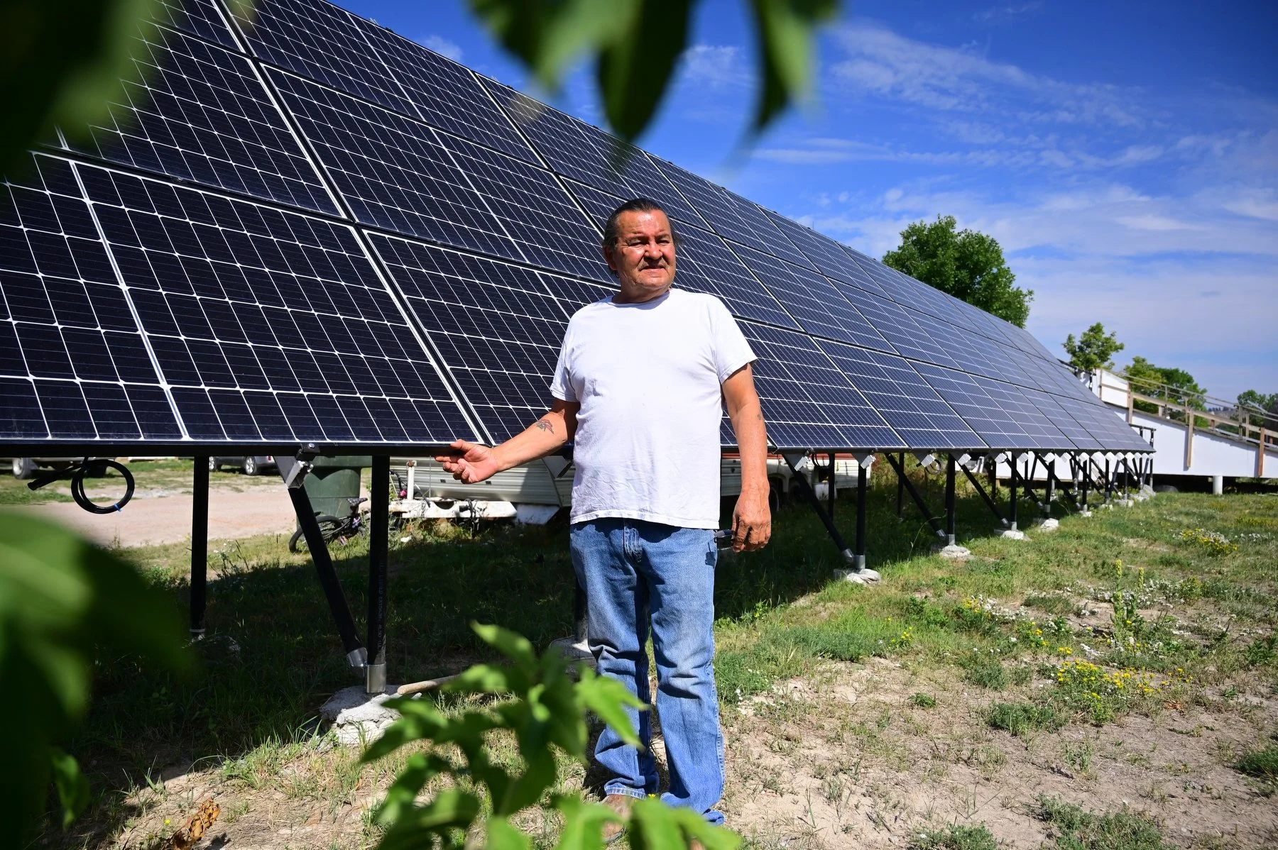  Henry Red Cloud poses for a portrait in front of a solar panel array at Red Cloud Renewables, October 2022.  